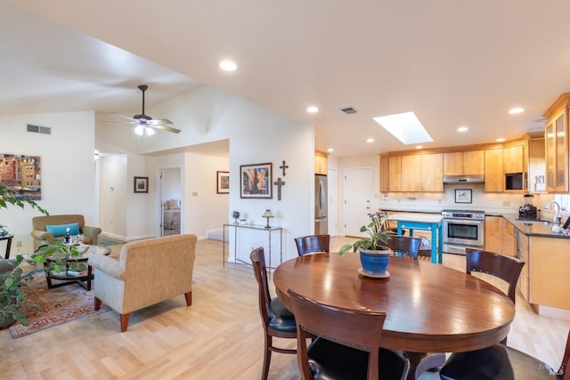 dining area featuring light wood finished floors, vaulted ceiling with skylight, visible vents, and recessed lighting