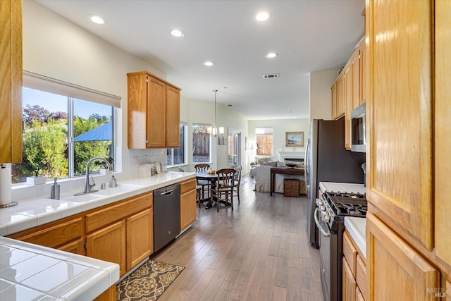 kitchen featuring sink, dark hardwood / wood-style flooring, hanging light fixtures, tile counters, and stainless steel appliances