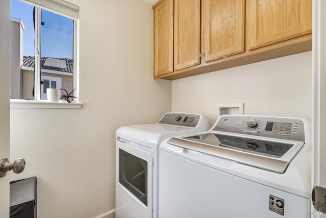 clothes washing area with washer and clothes dryer and cabinets