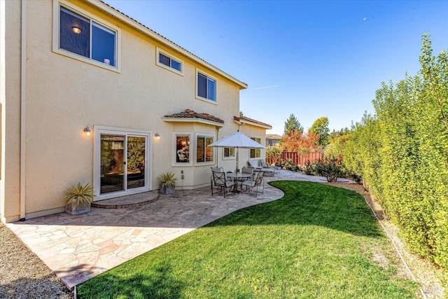 back of house featuring a lawn and a patio