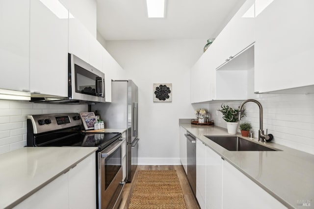 kitchen featuring white cabinetry, stainless steel appliances, sink, and backsplash