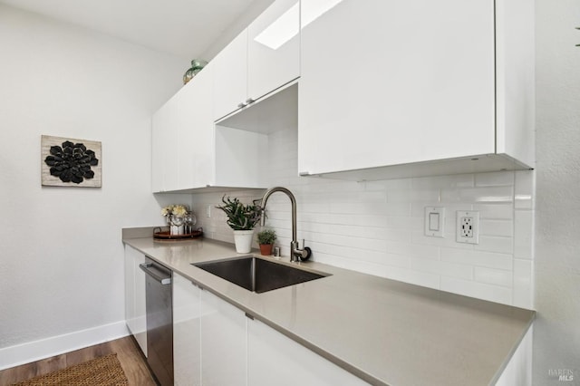 kitchen featuring hardwood / wood-style floors, tasteful backsplash, dishwasher, sink, and white cabinets