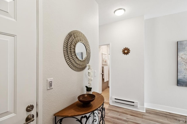 hallway with light hardwood / wood-style flooring and baseboard heating