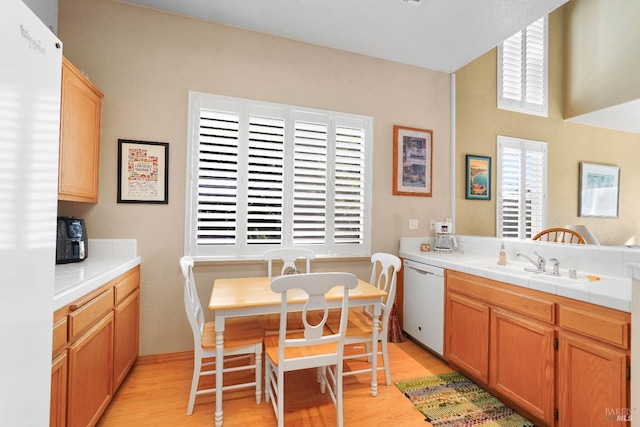 kitchen with sink, tile countertops, white dishwasher, and light hardwood / wood-style flooring