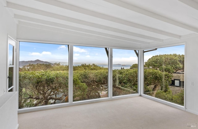 unfurnished sunroom with plenty of natural light, beam ceiling, and a water and mountain view