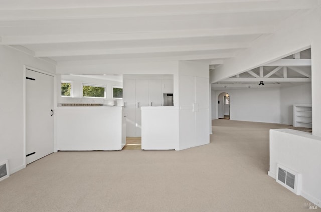 interior space featuring beam ceiling and light colored carpet