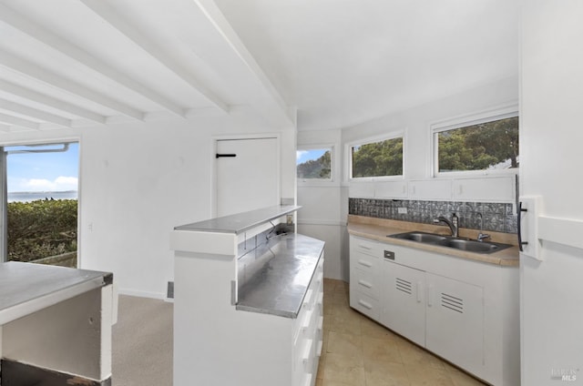 kitchen featuring white cabinetry, beam ceiling, sink, and tasteful backsplash