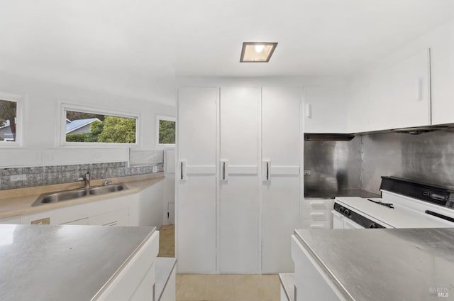 kitchen with white cabinetry, sink, decorative backsplash, and white stove