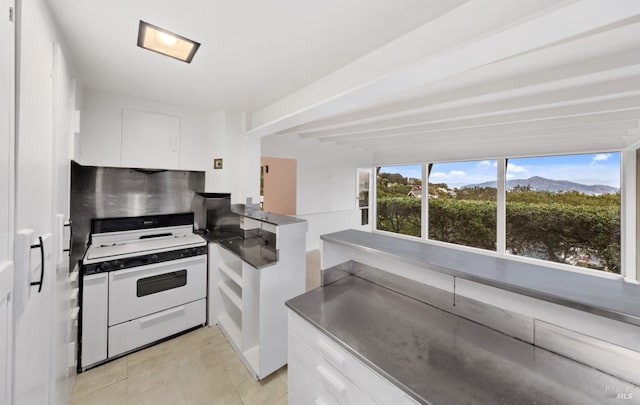 kitchen with light tile patterned flooring, white gas stove, and white cabinets