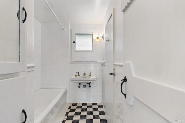 bathroom with sink, tile walls, and a bathtub