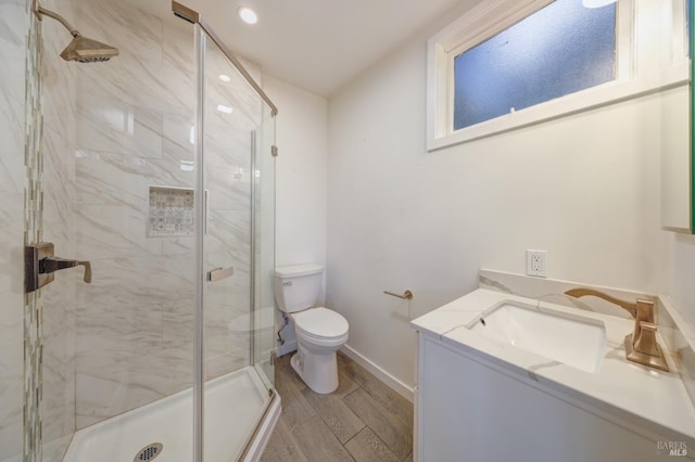 bathroom with a shower with door, vanity, and toilet