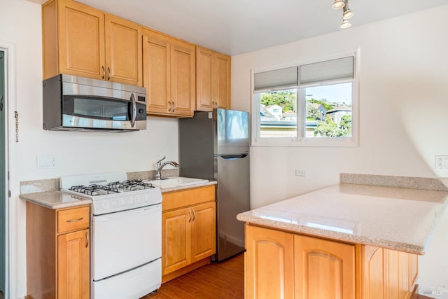 kitchen featuring light stone counters, sink, light wood-type flooring, and appliances with stainless steel finishes