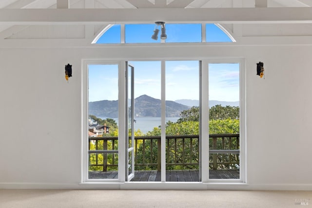 doorway to outside with lofted ceiling with beams, carpet, and a water and mountain view