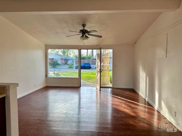 empty room featuring ceiling fan, vaulted ceiling, and dark hardwood / wood-style flooring