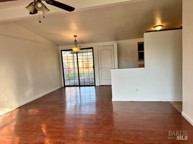 empty room with vaulted ceiling, ceiling fan, and dark hardwood / wood-style flooring