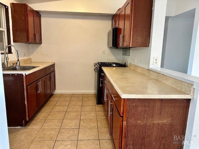 kitchen featuring range with gas stovetop, sink, and light tile patterned floors