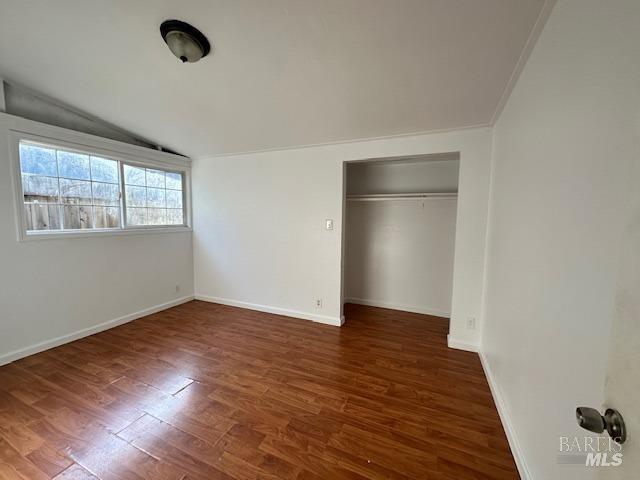 unfurnished bedroom with lofted ceiling, dark hardwood / wood-style flooring, and a closet