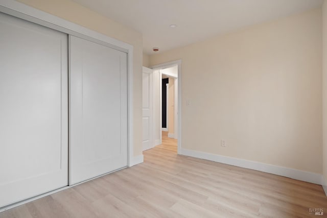 unfurnished bedroom featuring a closet and light wood-type flooring