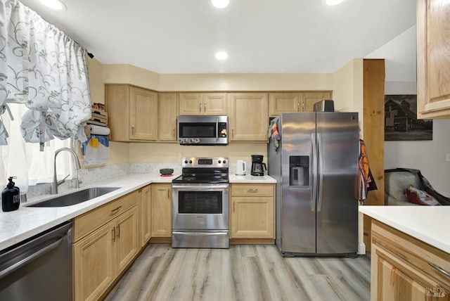 kitchen featuring appliances with stainless steel finishes, sink, light brown cabinetry, and light hardwood / wood-style flooring