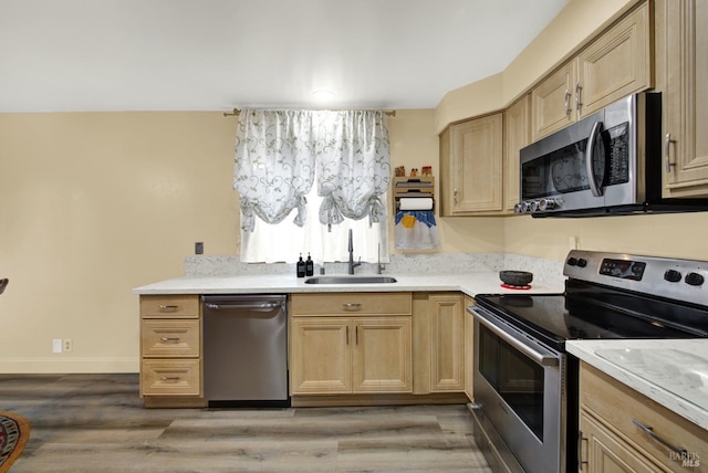 kitchen with sink, hardwood / wood-style flooring, stainless steel appliances, and light brown cabinets