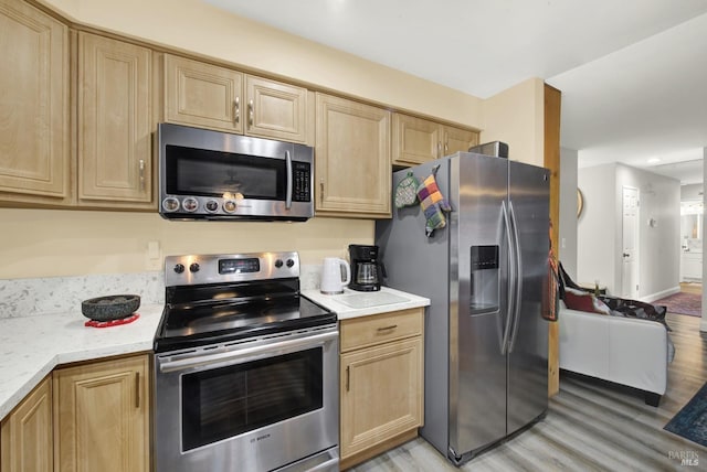 kitchen featuring appliances with stainless steel finishes, light brown cabinetry, and light wood-type flooring