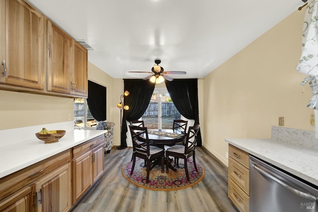 kitchen with ceiling fan, stainless steel dishwasher, light stone countertops, and hardwood / wood-style floors