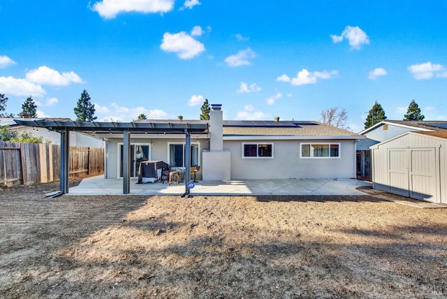 rear view of house with a shed, a patio area, and solar panels