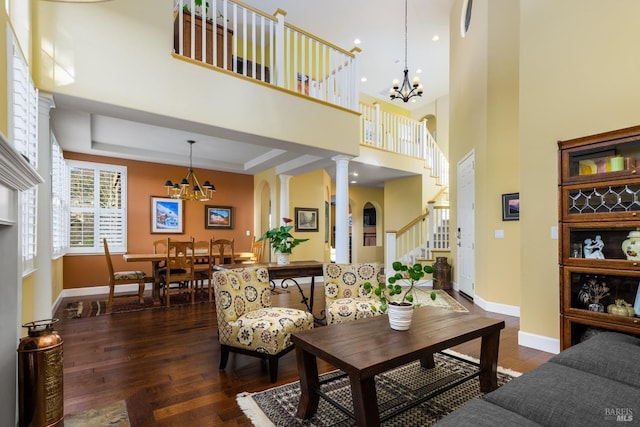 living room with dark hardwood / wood-style floors, a chandelier, and decorative columns