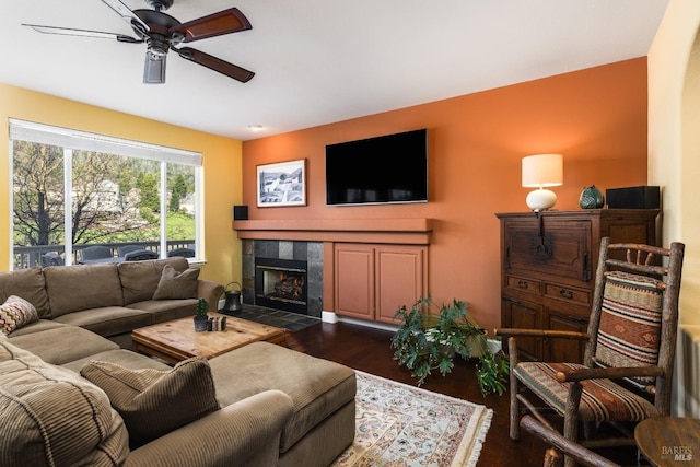 living room with ceiling fan, dark hardwood / wood-style floors, and a tile fireplace