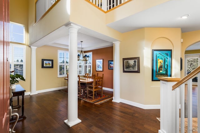 foyer with a towering ceiling, dark hardwood / wood-style floors, and ornate columns