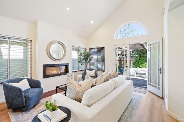 living room with high vaulted ceiling, light hardwood / wood-style floors, and french doors