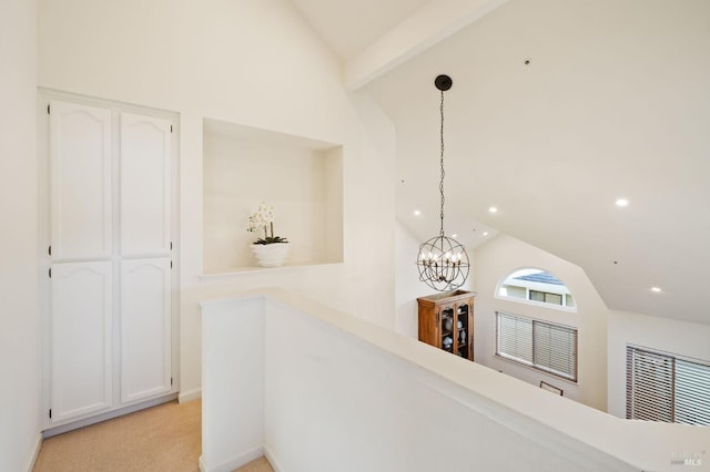 hallway featuring beam ceiling, high vaulted ceiling, light carpet, and a notable chandelier
