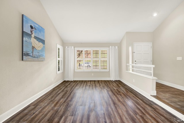 empty room with dark hardwood / wood-style flooring and vaulted ceiling