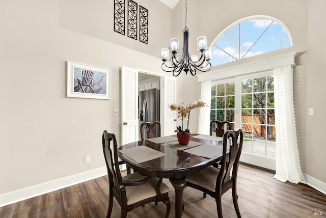 dining room featuring an inviting chandelier, wood-type flooring, and a high ceiling