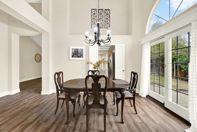 dining space featuring a high ceiling, hardwood / wood-style floors, and an inviting chandelier