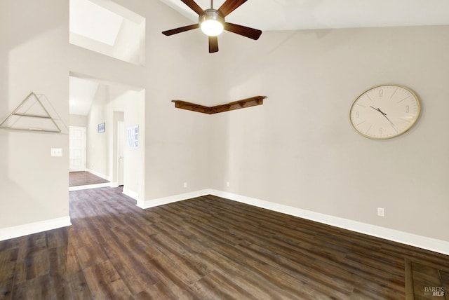 empty room with a skylight, dark wood-type flooring, high vaulted ceiling, and ceiling fan