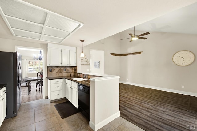 kitchen featuring pendant lighting, stainless steel refrigerator, black dishwasher, sink, and kitchen peninsula