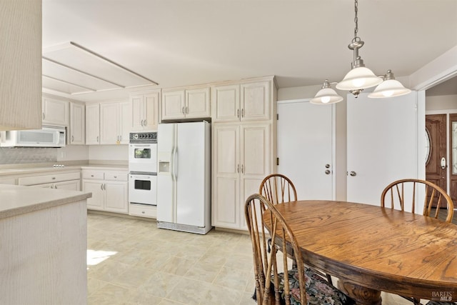 kitchen featuring white appliances, decorative light fixtures, and white cabinets