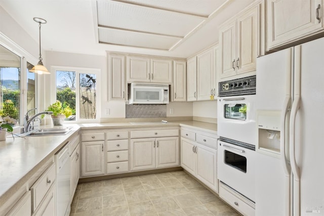 kitchen featuring hanging light fixtures, sink, and white appliances