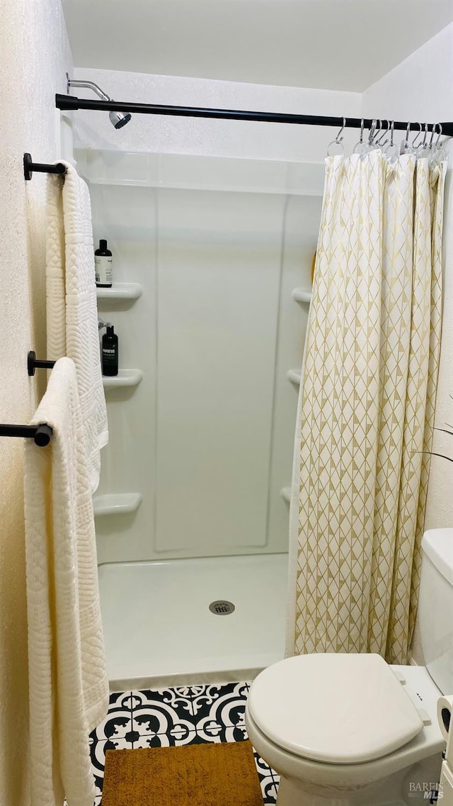 bathroom featuring walk in shower, tile patterned floors, and toilet