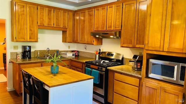 kitchen featuring a kitchen island, appliances with stainless steel finishes, sink, and hardwood / wood-style floors