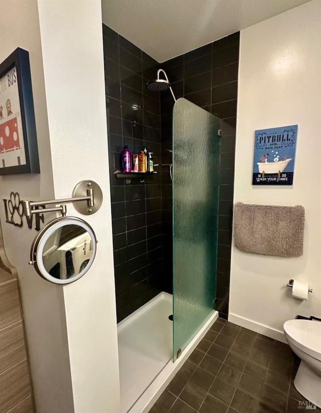 bathroom with a tile shower, tile patterned floors, and toilet