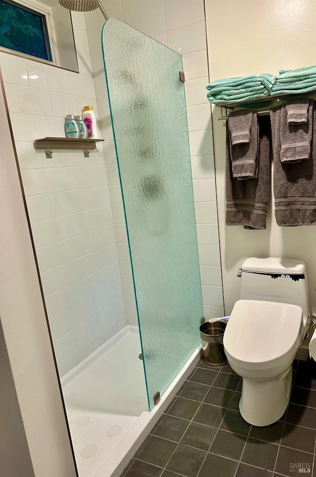 bathroom featuring tile patterned flooring, a tile shower, and toilet