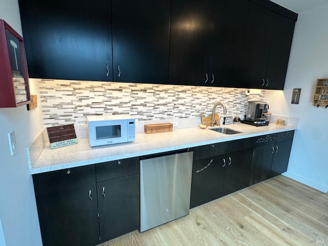 kitchen with stainless steel refrigerator, dishwasher, sink, decorative backsplash, and light hardwood / wood-style floors