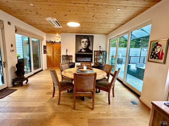 dining space with a wealth of natural light, wood ceiling, and light hardwood / wood-style flooring