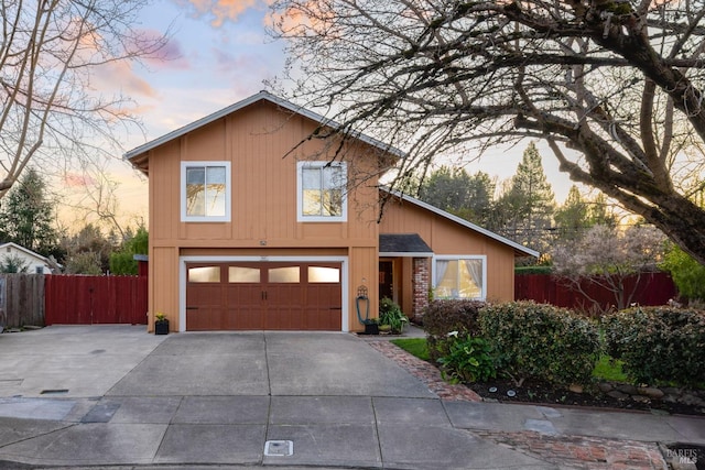 view of front of property featuring a garage, driveway, brick siding, and fence