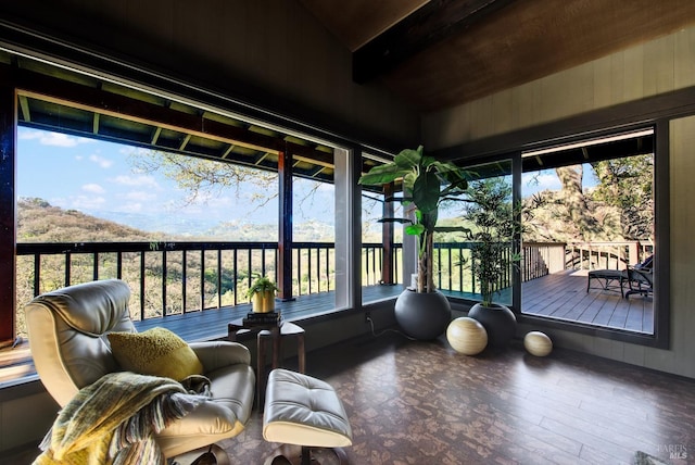 sunroom / solarium with a wooden deck, plenty of natural light, vaulted ceiling with beams, and wood finished floors