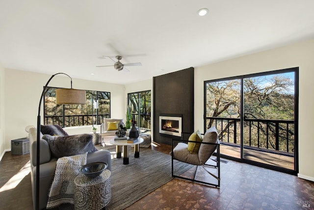 living room with plenty of natural light, a ceiling fan, baseboards, and a large fireplace