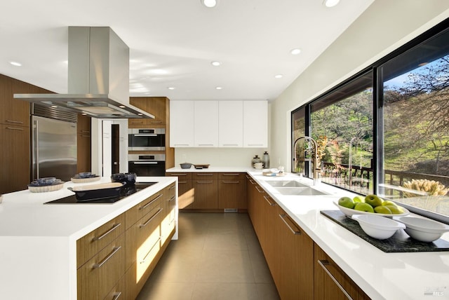 kitchen featuring stainless steel appliances, island exhaust hood, a sink, modern cabinets, and light countertops