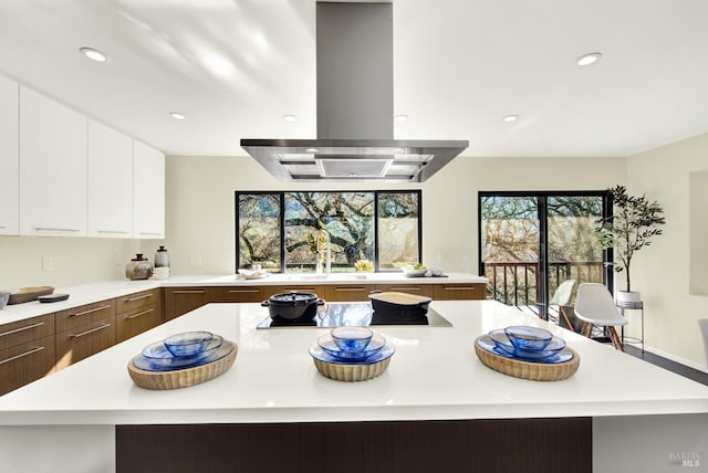 kitchen with modern cabinets, light countertops, stovetop, and island range hood